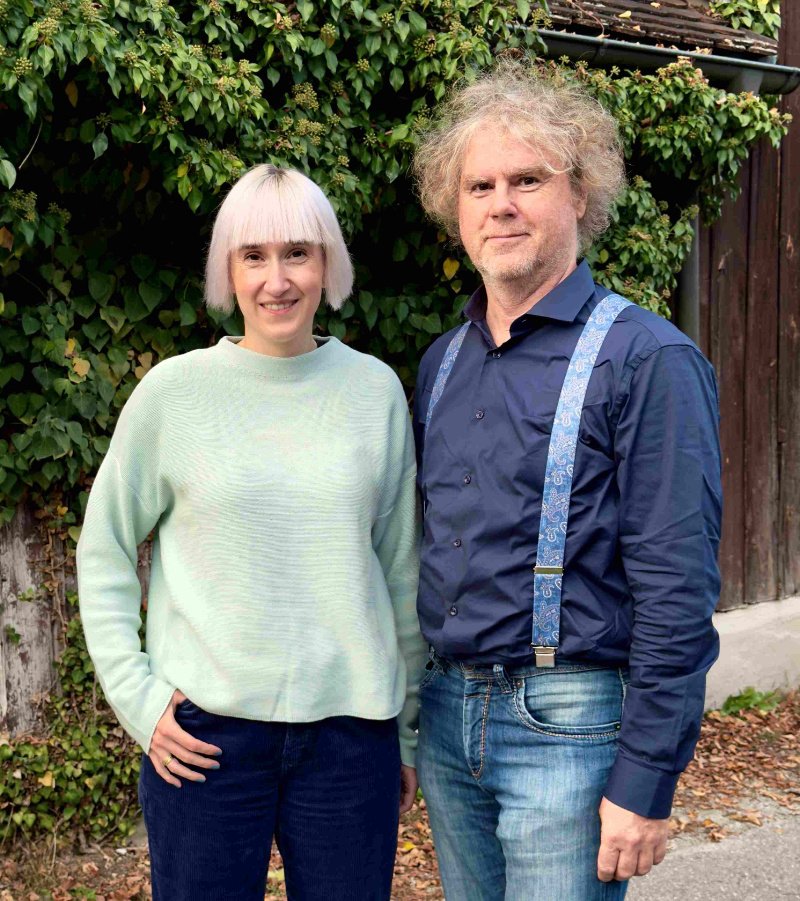 Stefanie Auer und Markus Scheuermann stehen vor einer begrünten Holzwand