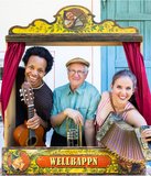 Hans Well, Sarah Well und Komale schauen mit Instrumeneten (Gitarre, Trompete, Ziehharmonika) aus einem alten Kaspertheater heraus