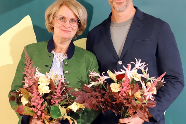 Spitzenduo Iris Haas und Christoph Rabl mit bunten Blumensträußen vor einem Grünen-Rollup