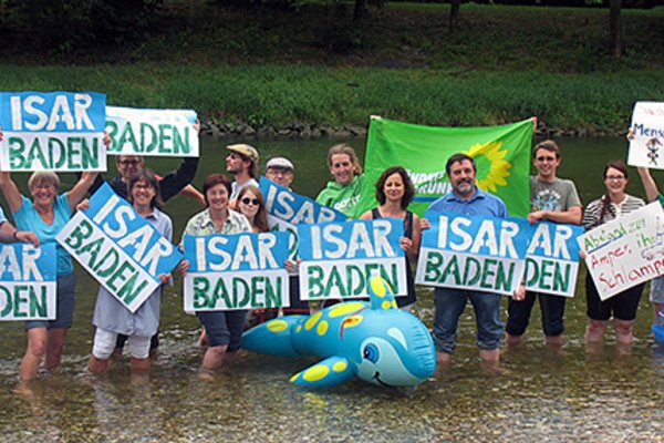 Viele Menschen stehen mit Protestschildern "Isar Baden" in der Isar