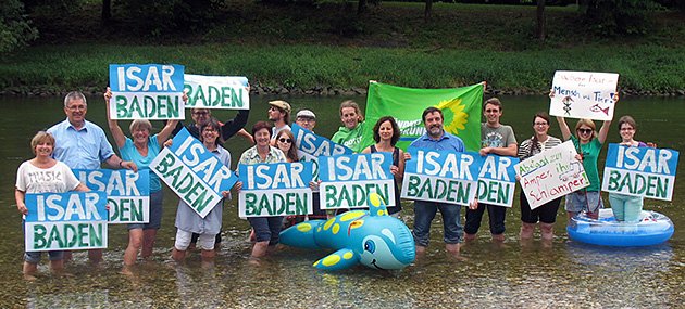 Viele Menschen stehen mit Protestschildern "Isar Baden" in der Isar