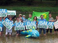 Viele Menschen stehen mit Protestschildern "Isar Baden" in der Isar