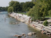 Fluß mit großen Treppen hinein, auf denen viele Menschen sitzen, einige baden