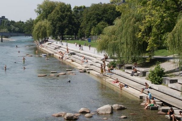 Fluß mit großen Treppen hinein, auf denen viele Menschen sitzen, einige baden