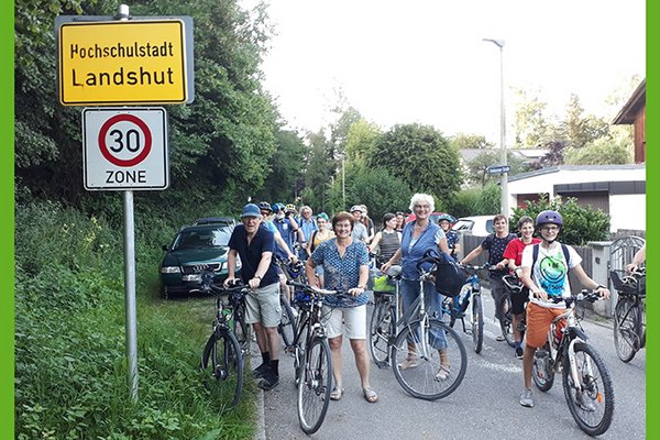 viele Radfahrer warten auf der Roßbachstraße vor dem Ortsschild "Hochschulstadt Landshut"