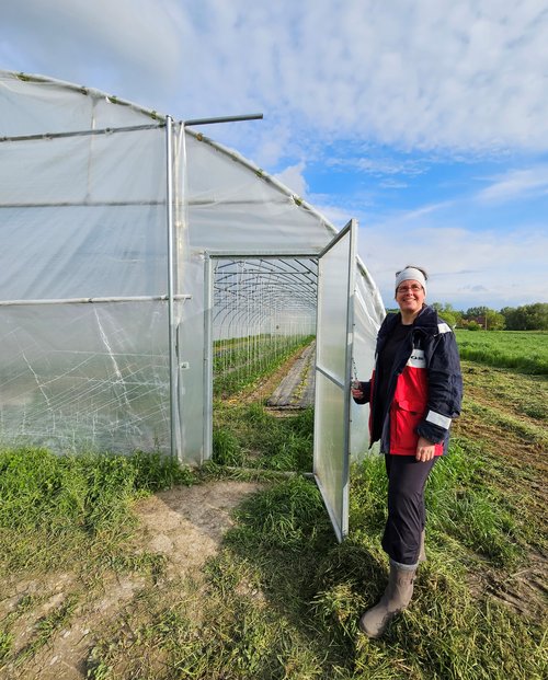 Annette Theißen steht vor dem geöffneten Zugang zu einem Folientunnel