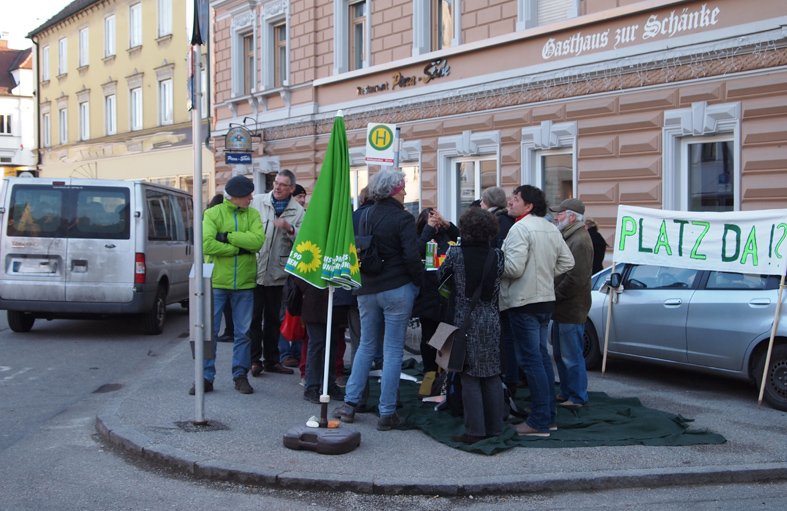 mehrere Personen mit Tisch auf einem grünen Teppich vor der Pizzeria am Bismarckplatz