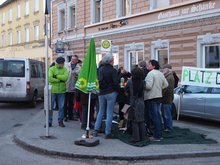 mehrere Personen mit Tisch auf einem grünen Teppich vor der Pizzeria am Bismarckplatz