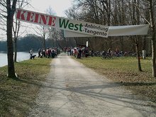 Keine West-Anbindung-, -Tangente-Transparent vor vielen demonstrierenden Menschen in der Isarau am Ort der geplanten Trassenführung
