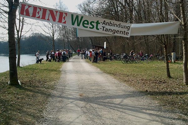 Keine West-Anbindung-, -Tangente-Transparent vor vielen demonstrierenden Menschen in der Isarau am Ort der geplanten Trassenführung