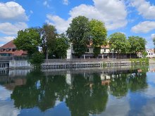 das Gasthaus "Zur Insel" mit Biergarten unter Bäumen von der Altstadtseite aus betrachtet, im Vordergrund die Isar