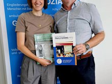 Bezirksrat und Beauftragter für Menschen mit Behinderung Markus Scheuermann und seine Fraktionskollegin Stefanie Auer präsentieren zwei Inklusions-Hefte von 2012 und 2025