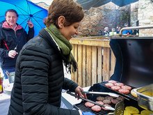 Stefan Gruber hält einen Schirm und Sigi Hagl grillt Burger im Regen