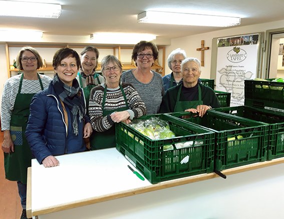 die Damen der Landshuter Tafel mit Sigi Hagl (2.v.l) hinter dem Tresen, auf dem grüne Gemüsekisten stehen in einem hell erleuchteten Raum