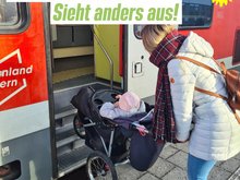 Junge Frau mit Kinderwagen müht sich ab, diesen über Stufen in einem Eisenbahnwaggon zu hieven. Schrift: Barrierefreiheit? Sieht anders aus!