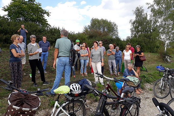 Viele Zuhörer beim Vortrag im Freien, im Vordergrund Fahrräder