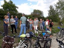 Viele Zuhörer beim Vortrag im Freien, im Vordergrund Fahrräder