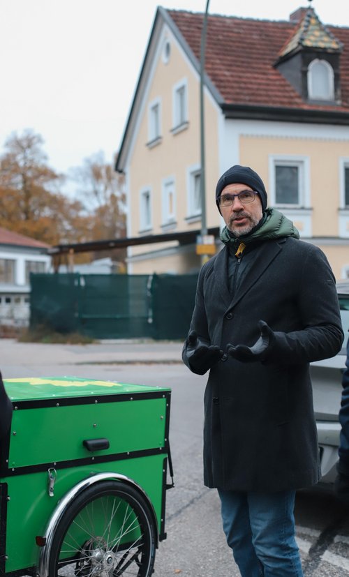 Christoph Rabl steht neben grünem Lastenrad und schaut zum Fotografen