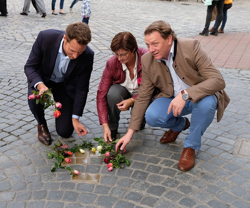 MdL Rosi Steinberger, MdL Ludwig Hartmann und Stadtrat Stefan Gruber legen Blumen bei den Stolpertseinen in der Theaterstrasse nieder