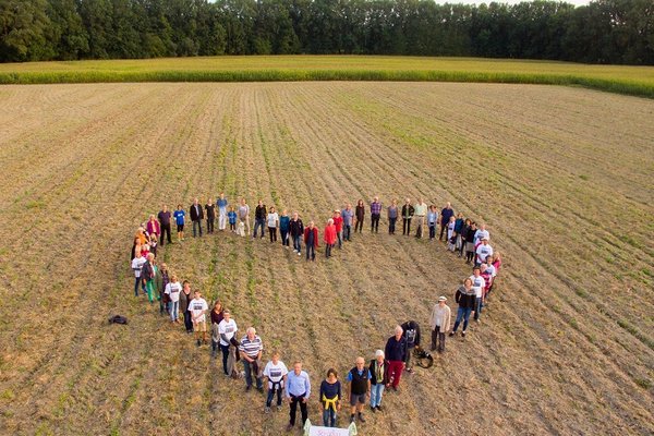 Viele Menschen stehen in Herzform auf einem abgeernteten Feld nahe der geplanten Trasse der Westtangente.