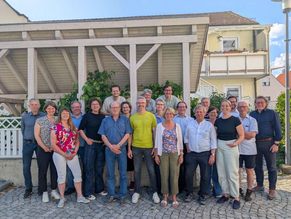 größere Gruppe der Grünen Mitglieder vor einer weißen Terrassen-Überdachung aus Holz, im Hintergrund ein weiteres Haus