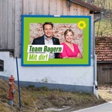 Ludwig Hartmann und Katharina Schulze auf einer Großfläche an einer holzbeplankten Stadelwand